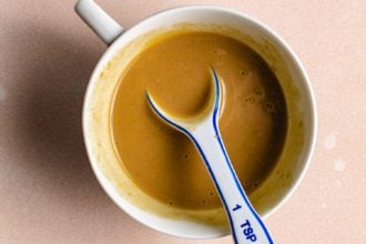 Honey mustard sauce in a cup with measuring spoon