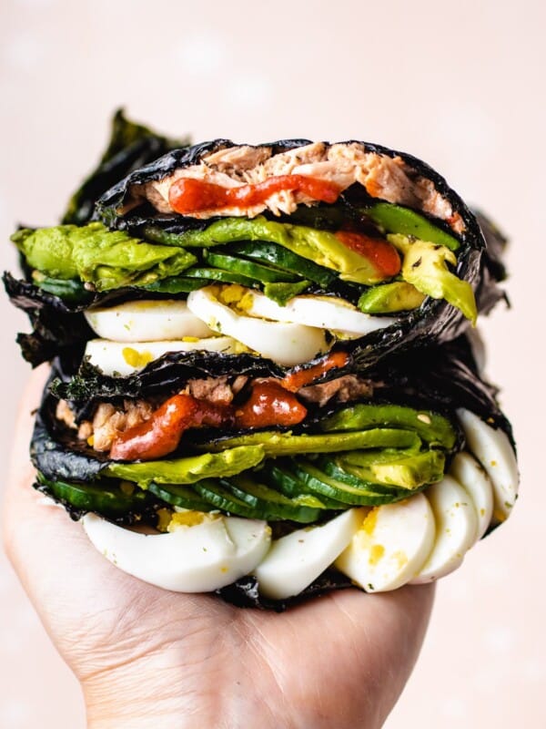 Photo shows one hand holding the stacks of food wrapped in nori sheets