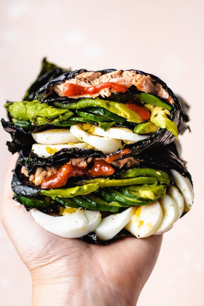 Photo shows one hand holding the stacks of food wrapped in nori sheets