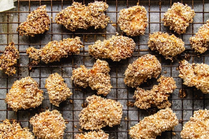Chicken cubes coated with sesame seeds over a wire rack sheet pan