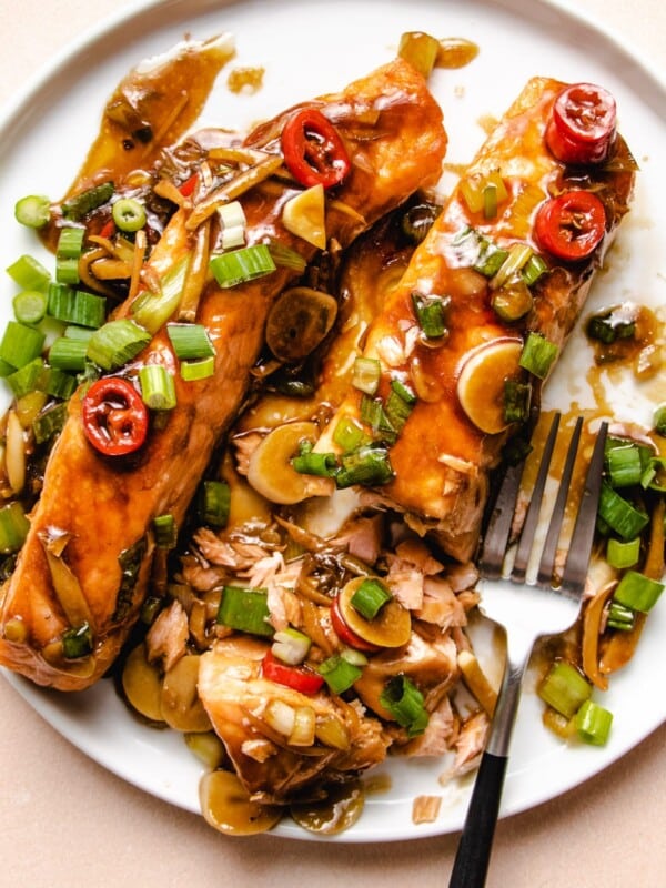 Two pieces of salmon fillets glazed in ginger sauce on a white plate