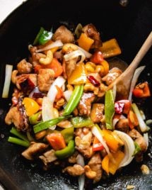 Photo shows stir fried chicken and cashew nuts with sauce in a big wok