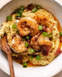 A white bowl with thick creamy almond meal grits and shrimp on top