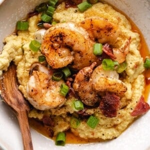 A white bowl with thick creamy almond meal grits and shrimp on top