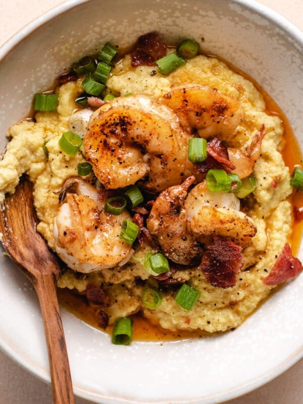 A white bowl with thick creamy almond meal grits and shrimp on top