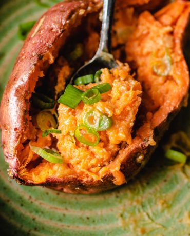 Photo shows a spoonful of oven baked sweet potatoes sprinkled with scallions