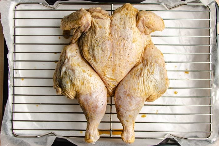Photo shows spatchcocked chicken prepared to roast in the oven site over a wired rack