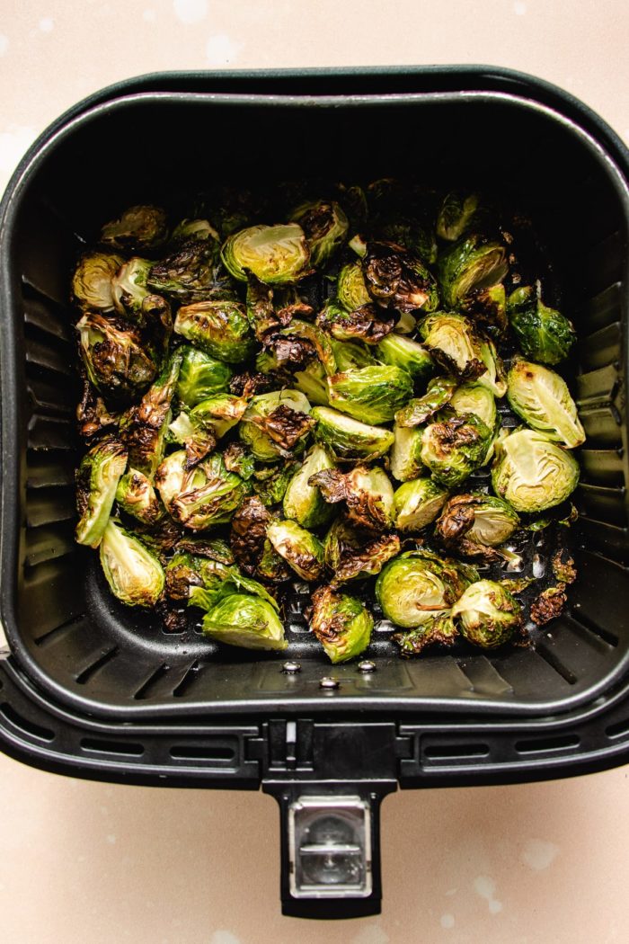 Photo shows brussels sprouts air fried to crispy in a fryer basket