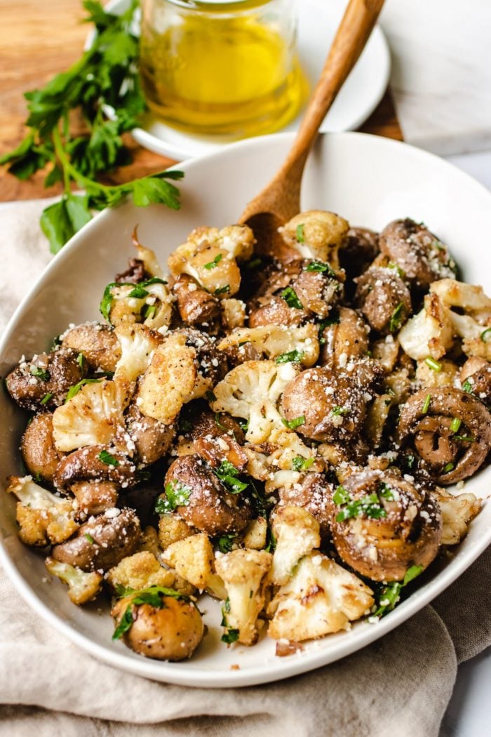 Photo shows mushrooms sauteed with cauliflower serve on a big white oval plate