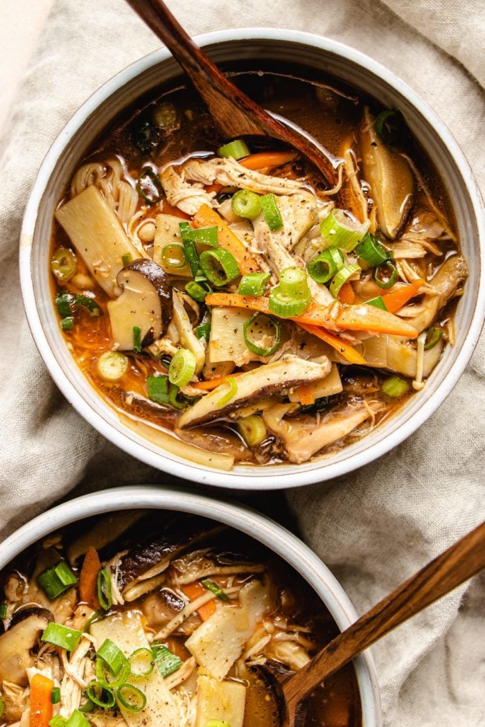 Photo shows two serving white color bowl with Chinese hot sour soup and spoons