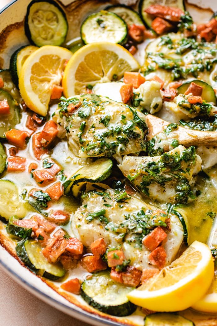 photo shows baked cod fillets covered with herb butter on top and melted in the pan