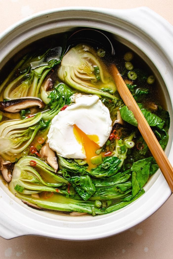 Photo shows a white clay soup pot with poached eggs and baby bok choy