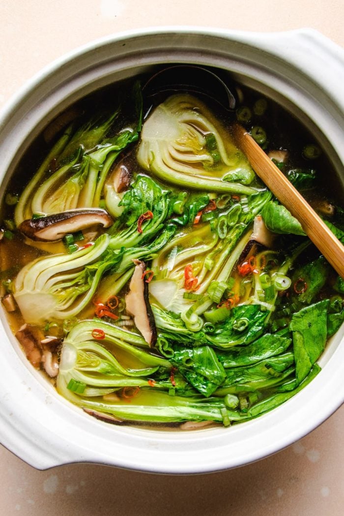 Photo shows a big white clay soup pot with baby bok choy with shiitake soup