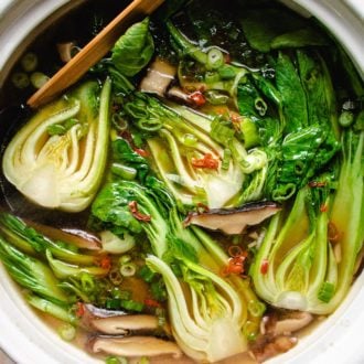 Photo shows baby bok choy cooked in a big white clay pot soup