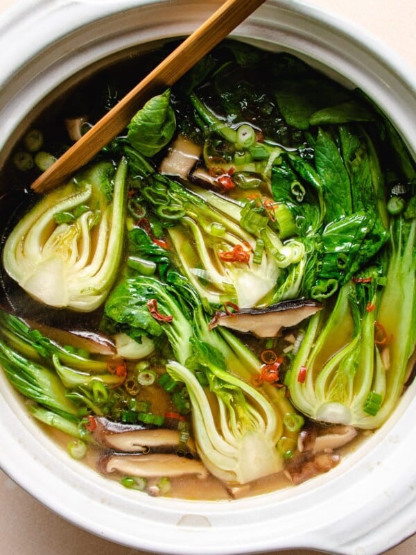 Photo shows baby bok choy cooked in a big white clay pot soup.