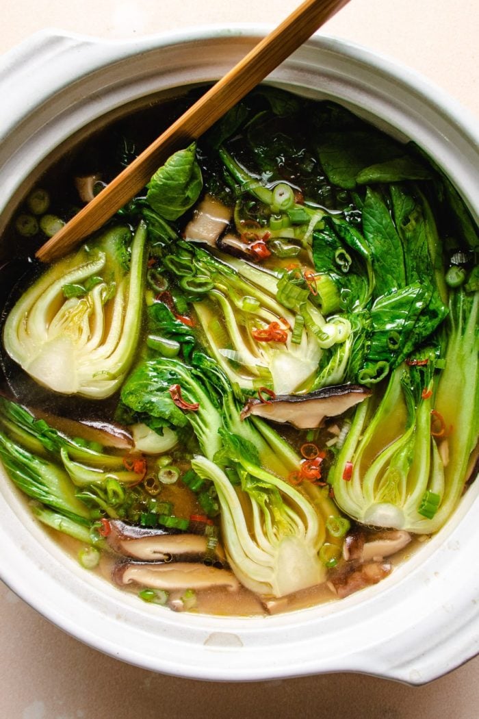 Photo shows baby bok choy cooked in a big white clay pot soup