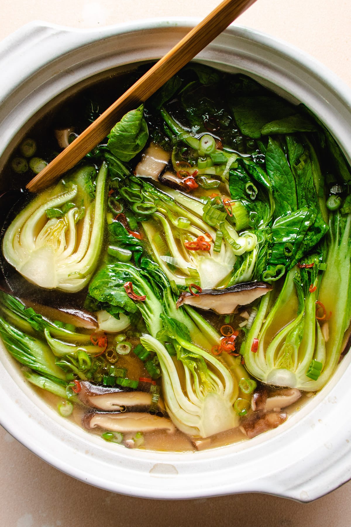Photo shows baby bok choy cooked in a big white clay pot soup.