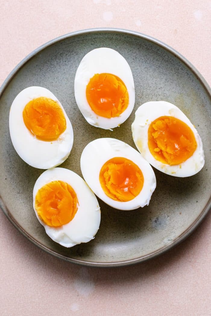 Photo shows hard boiled air fryer eggs sliced in half placed on a gray plate
