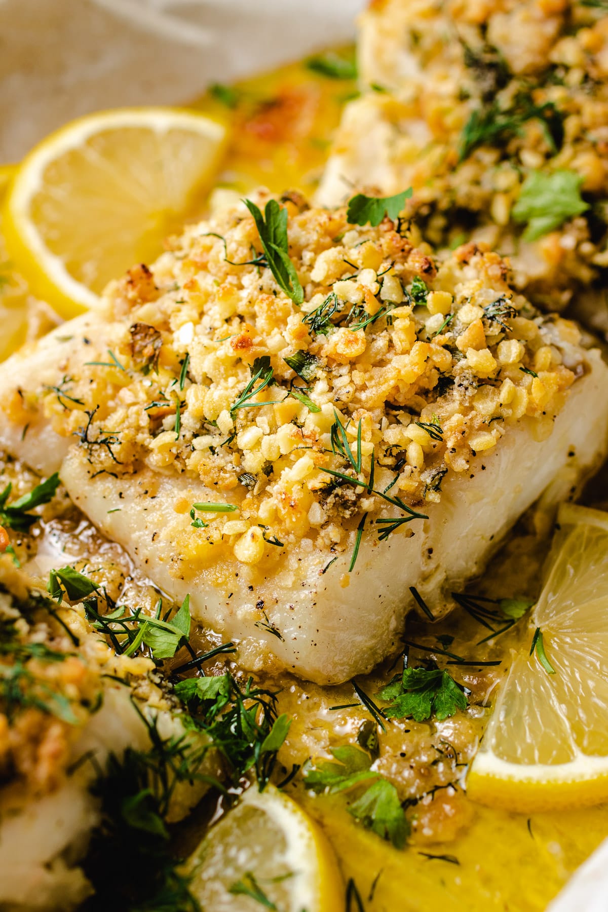 A close shot shows baked panko crust with cod served with lemon on the side