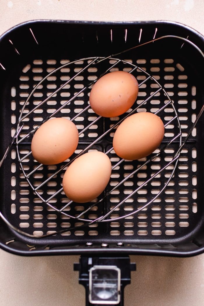 Photo shows place 4 whole eggs on a wire rack inside of air fryer basket