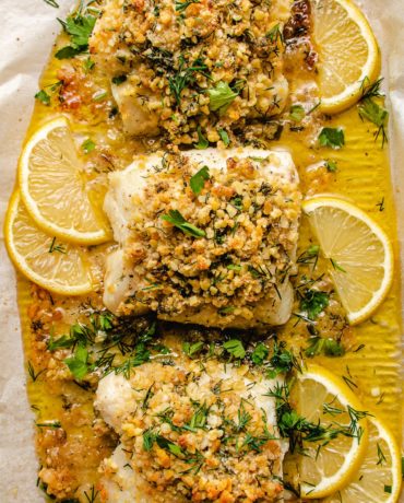 Photo shows 3 cod fillets with panko crust baked in a sheet pan with lemon butter sauce