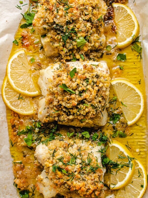 Photo shows 3 cod fillets with panko crust baked in a sheet pan with lemon butter sauce