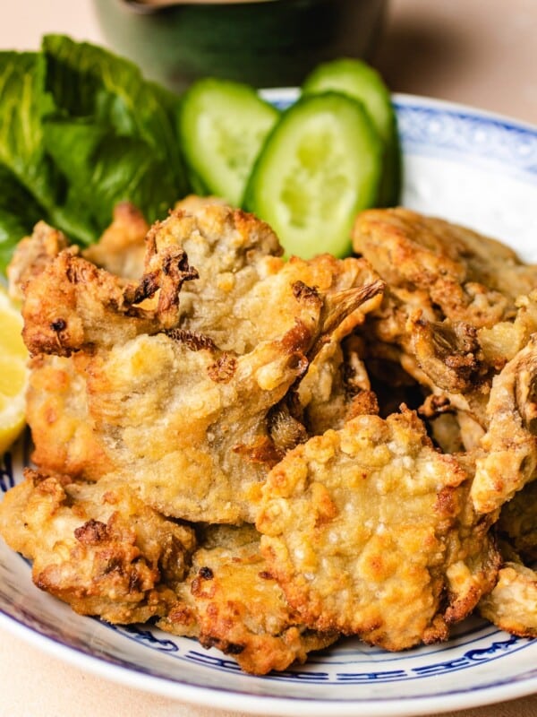 Photo shows fried oyster mushrooms on a blue white color plate with sauce on the side