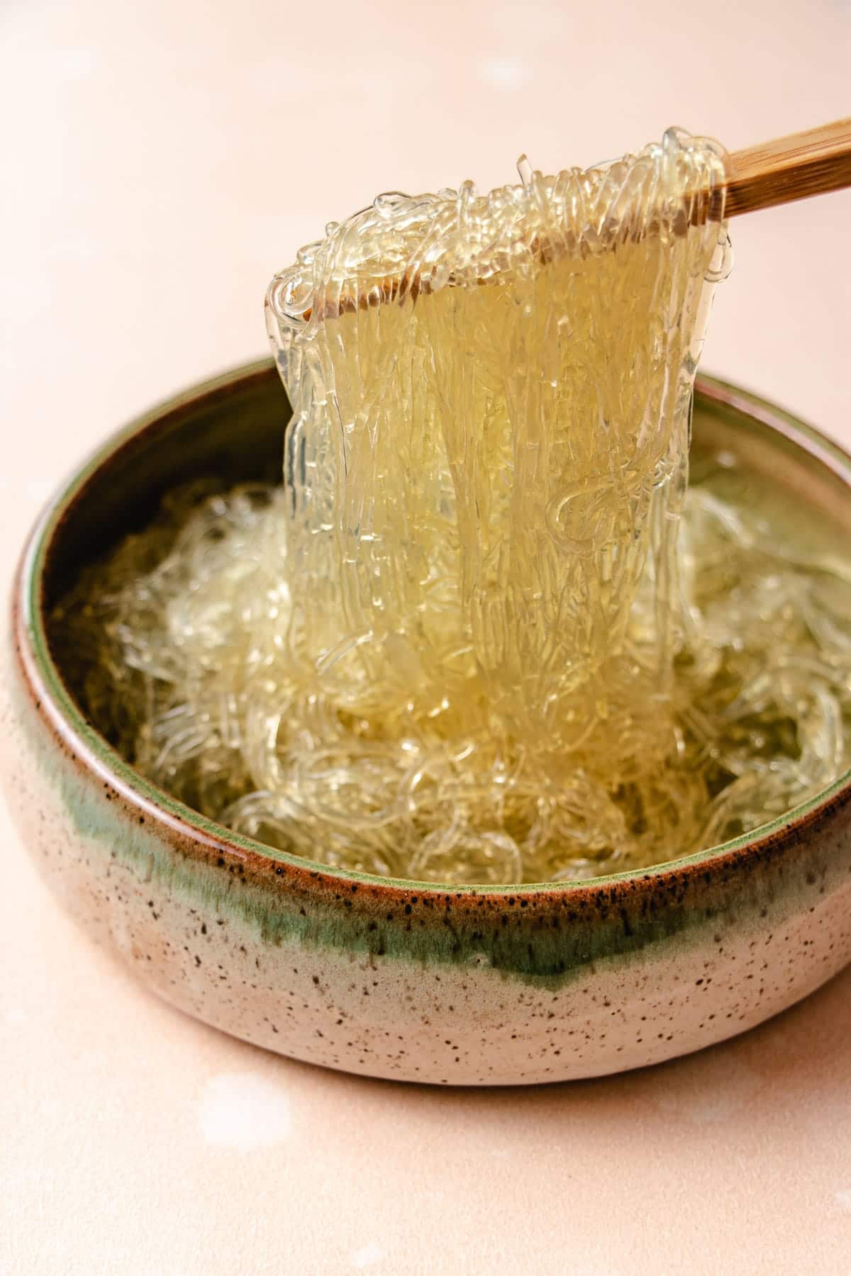 A side close shot shows glass noodles made with kelp that's softened and picking them up with chopsticks