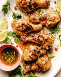 Photo shows 6 grilled chicken legs drizzled with sauce on a big white oval plate