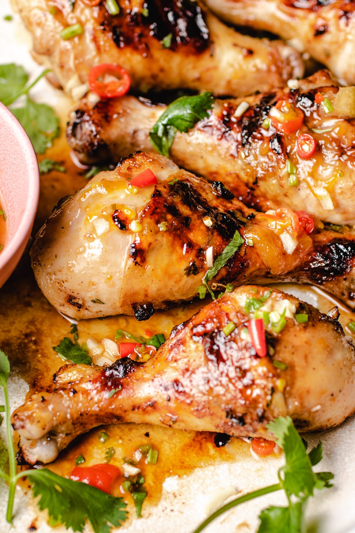 A side close shot shows juicy chicken legs grilled and covered with sweet chili bbq sauce
