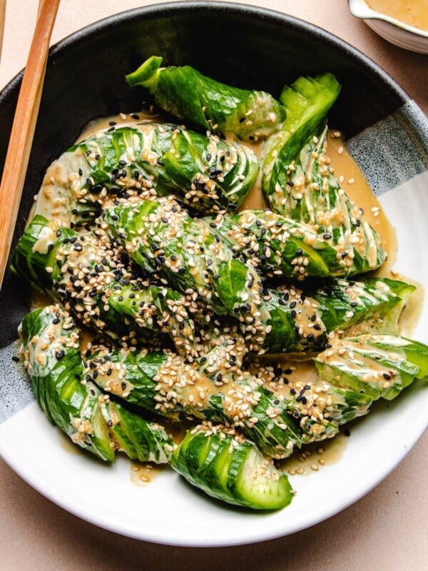 A close shot of the Japanese cucumbers with spiralized cut and dressing on a black white plate.