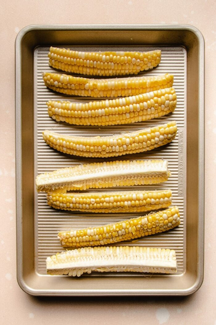 Photo shows placing the sliced corn cobs on a sheet pan