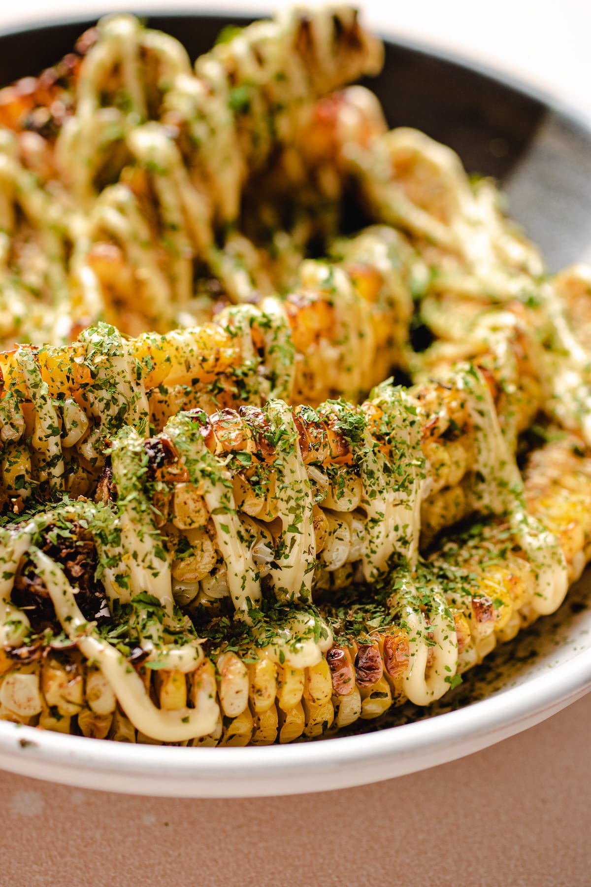 A close shot shows air fryer corn on the cob with mayo over the top