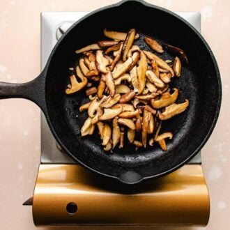 Photo shows sauteed shiitake in a cast iron pan on the stove