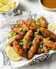 Photo shows a plate of air fried chicken lemon pepper wings served with lemon on the side and the sauce