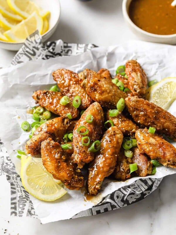 Photo shows a plate of air fried chicken lemon pepper wings served with lemon on the side and the sauce