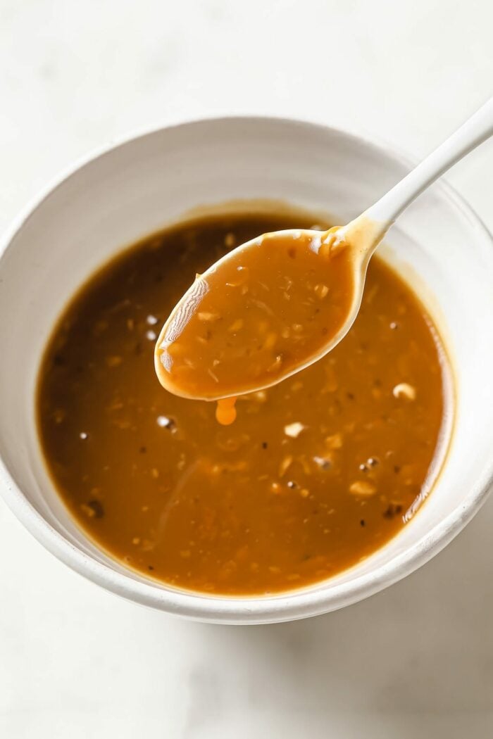 Lemon pepper sauce in a white bowl and a spoon over the sauce