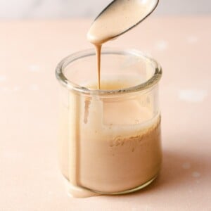 A spoonful of bam bam sauce dripping out of the glass jar