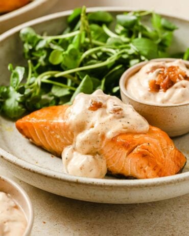 Frozen salmon.air fryer with bacon aioli and salad greens served on a creamed color plate