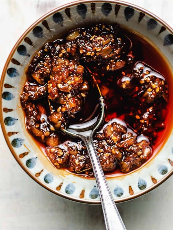 Homemade chili garlic sauce served in a light colored bowl with a spoon in the bowl