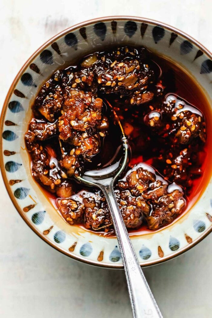 Homemade chili garlic sauce served in a light colored bowl with a spoon in the bowl