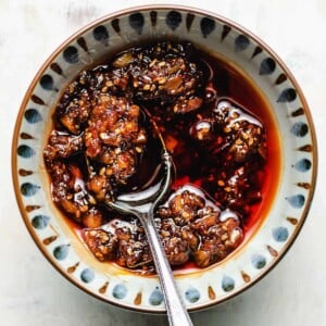 Garlic chili sauce recipe served in a light colored bowl with a spoon in the bowl