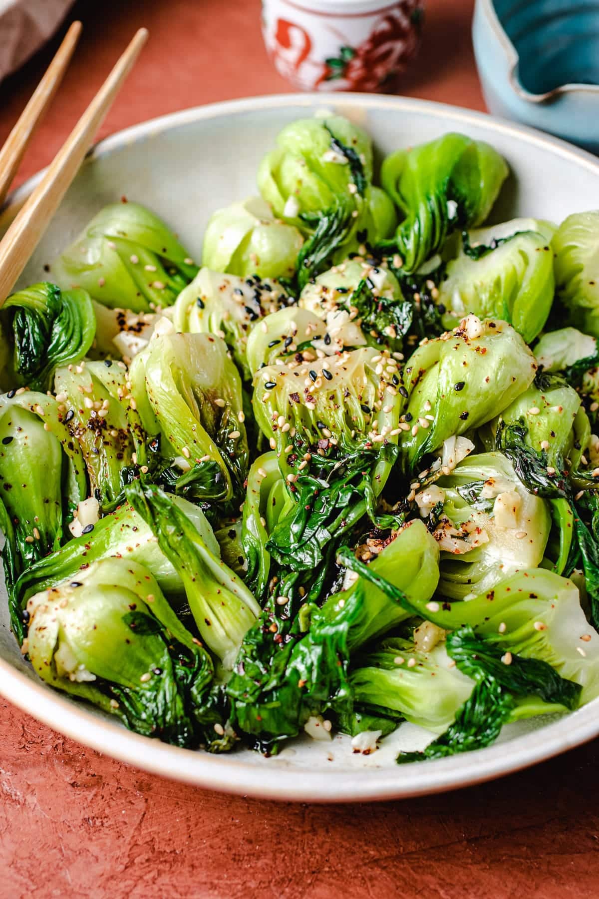 Chineses stir fried baby bok choy served in a white plate with chopsticks