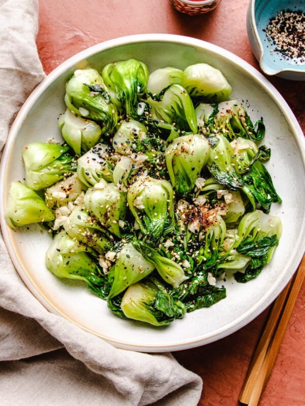 Bok choy stir fry served over a white plate with chopsticks on the side