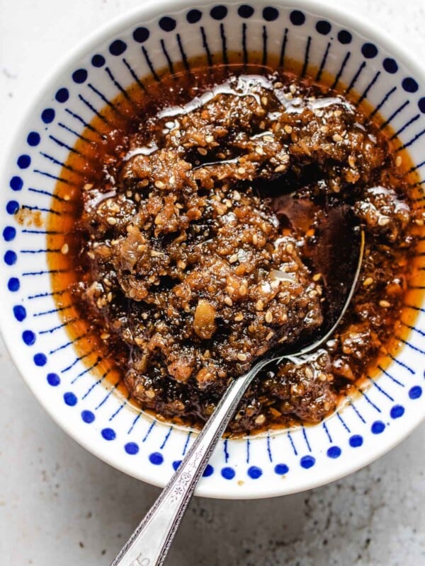 homemade sha cha sauce served in a blue white color small bowl with spoon inside.