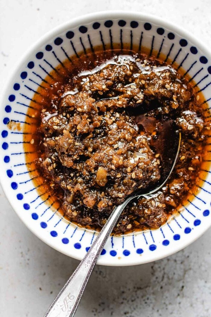 homemade sha cha sauce served in a blue white color small bowl with spoon inside.