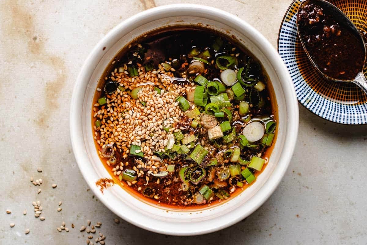 A close shot shows Chinese hotpot dipping spicy sauce in a bowl