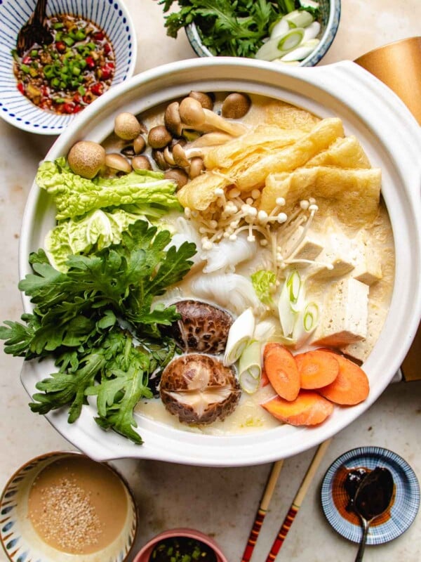 Photo shows a hot pot loaded with vegetables with dipping sauces on the side