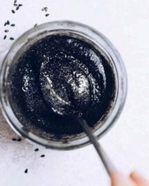 A close overhead shot shows black sesame paste stored in a glass jar with a spoon