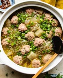 Winter melon and meatballs simmered in a big white clay soup pot with a ladle and extra sauce on the side